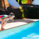 young toddler girl jumping into swimming pool